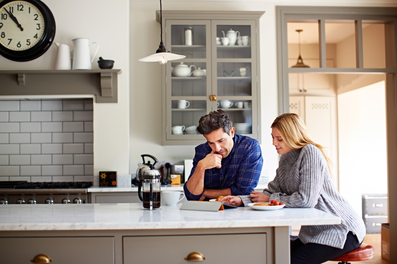 Shot of a young couple using a digital tablet while sitting at their kitchen table at home